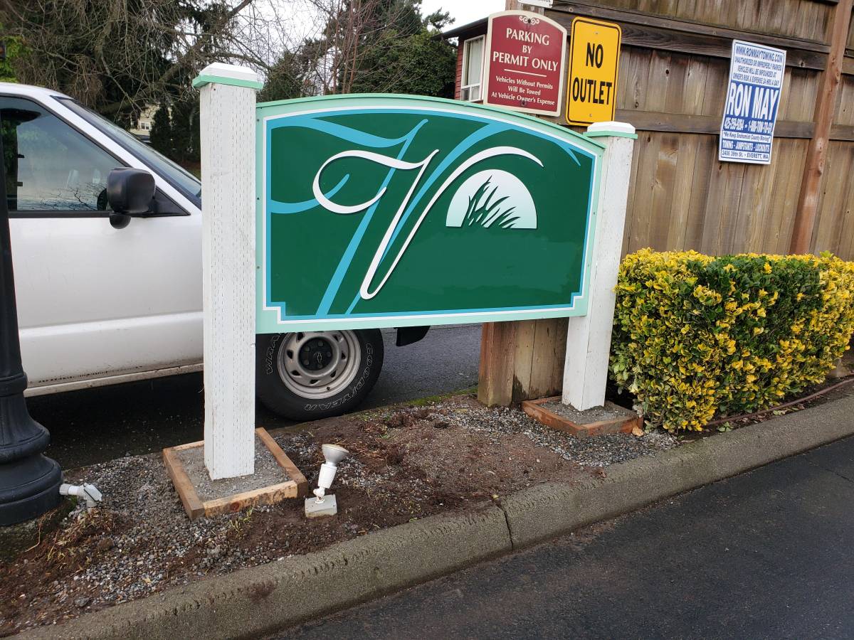 Outdoor sign installed on a post beside landscaping
